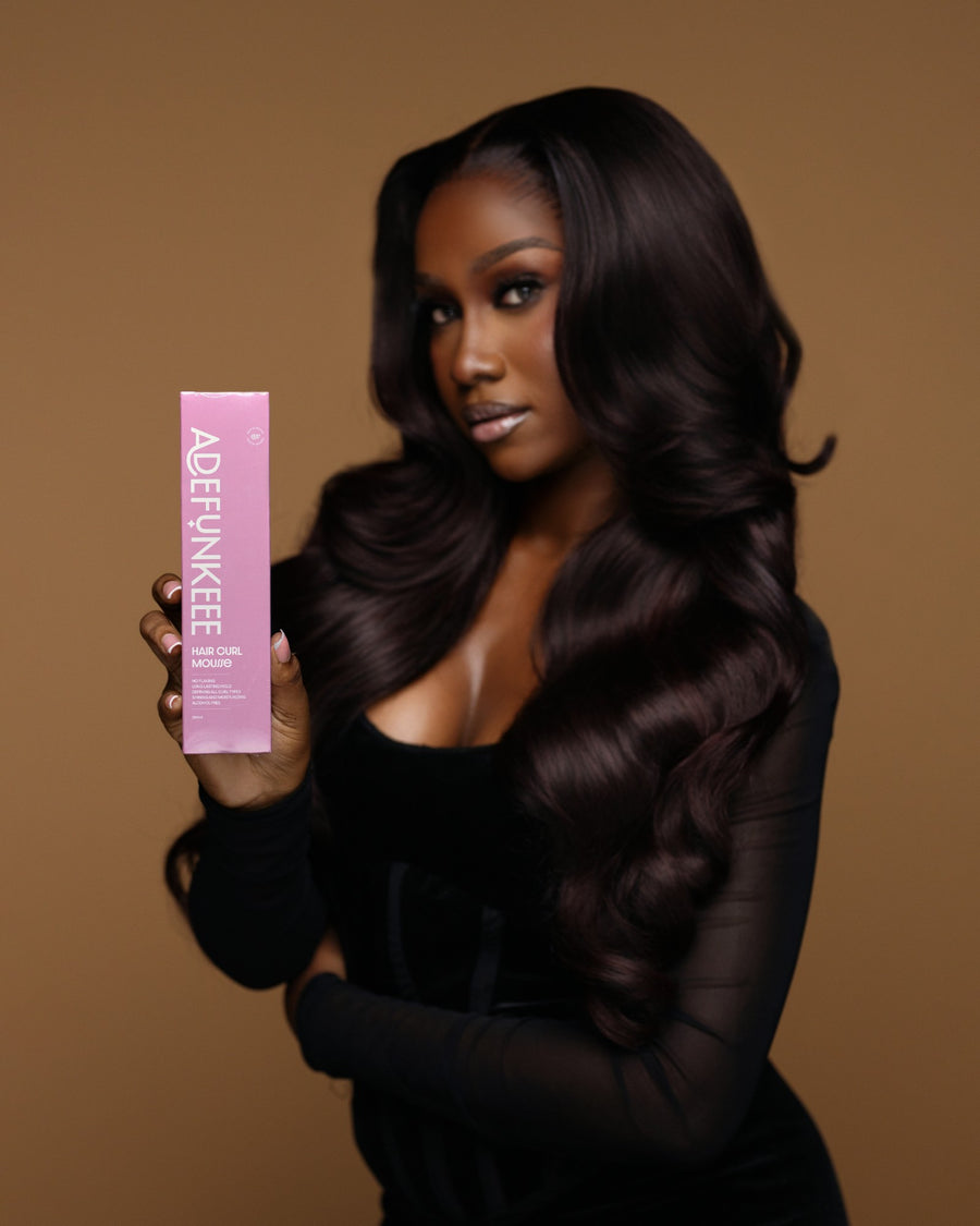 Model with long dark hair holding the Hair Curl Mousse box