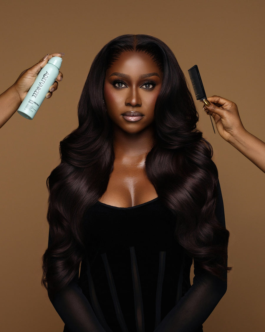 Lace Melting Spray held up beside a model with long, dark waves while a second hand combs her hair